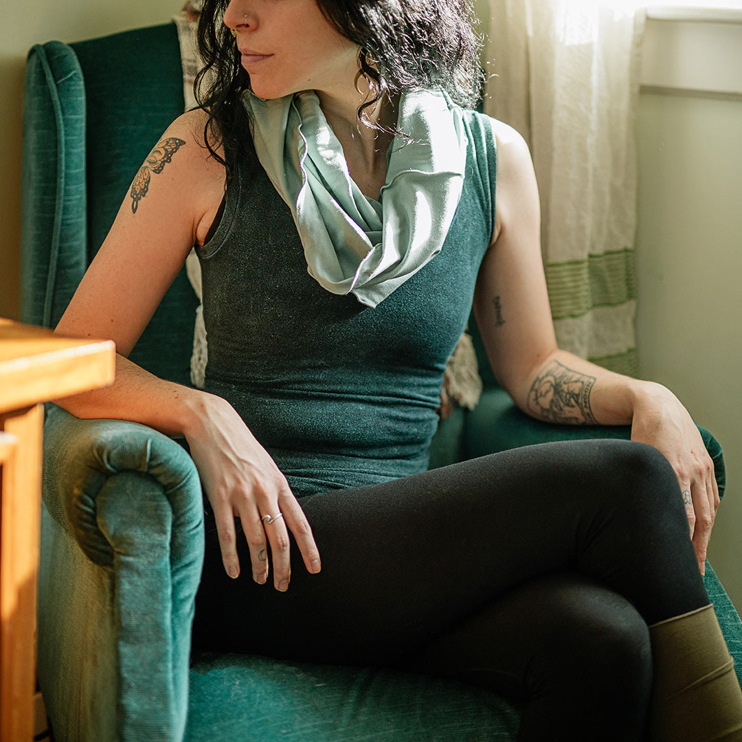 hourglass in glass around the neck, blue mineral core tank, black base legging, and olive stockings