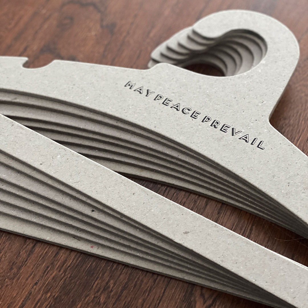 Perchas de cartón reciclado con la palabra paz