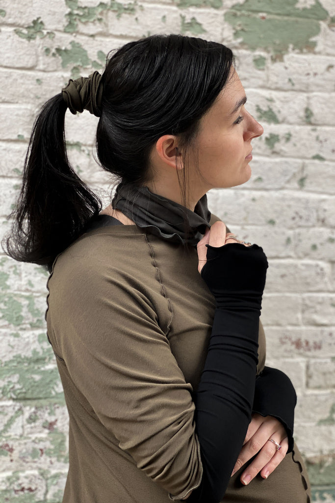 the band in olive secures ponytail with ore around the neck