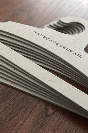 Perchas de cartón reciclado con la palabra paz