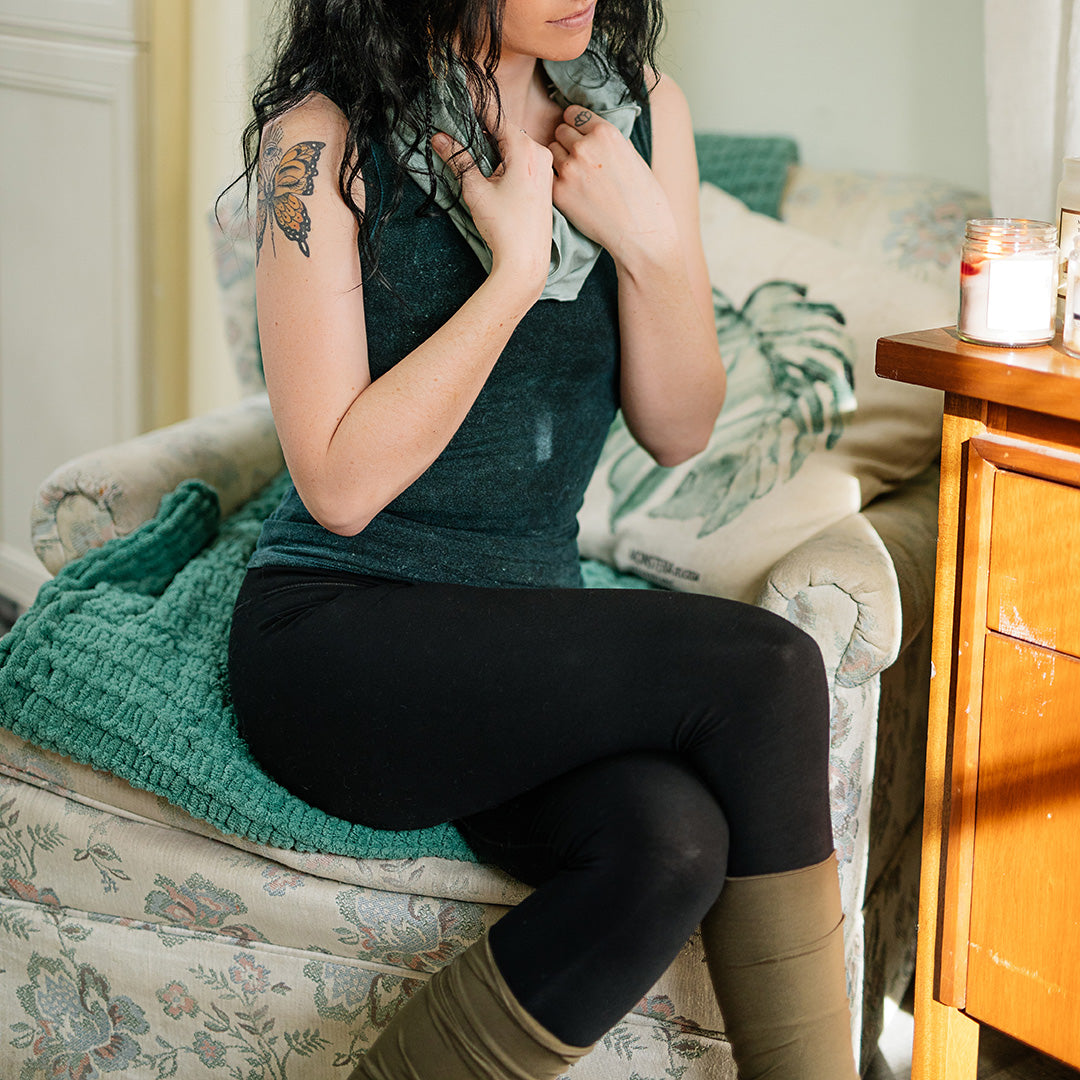 base legging in black paired with blue mineral core tank, glass hourglass around neck, and olive stocking