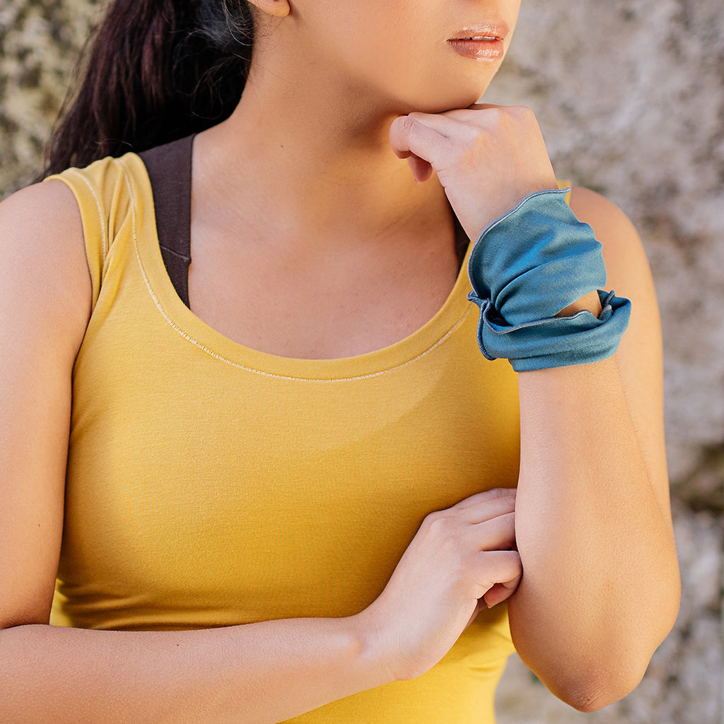 the band in ocean worn around the wrist paired with core tank in amber