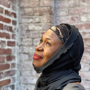 hourglass in subtle black worn as a cozy hood, with a hand dye band elegantly peeking through