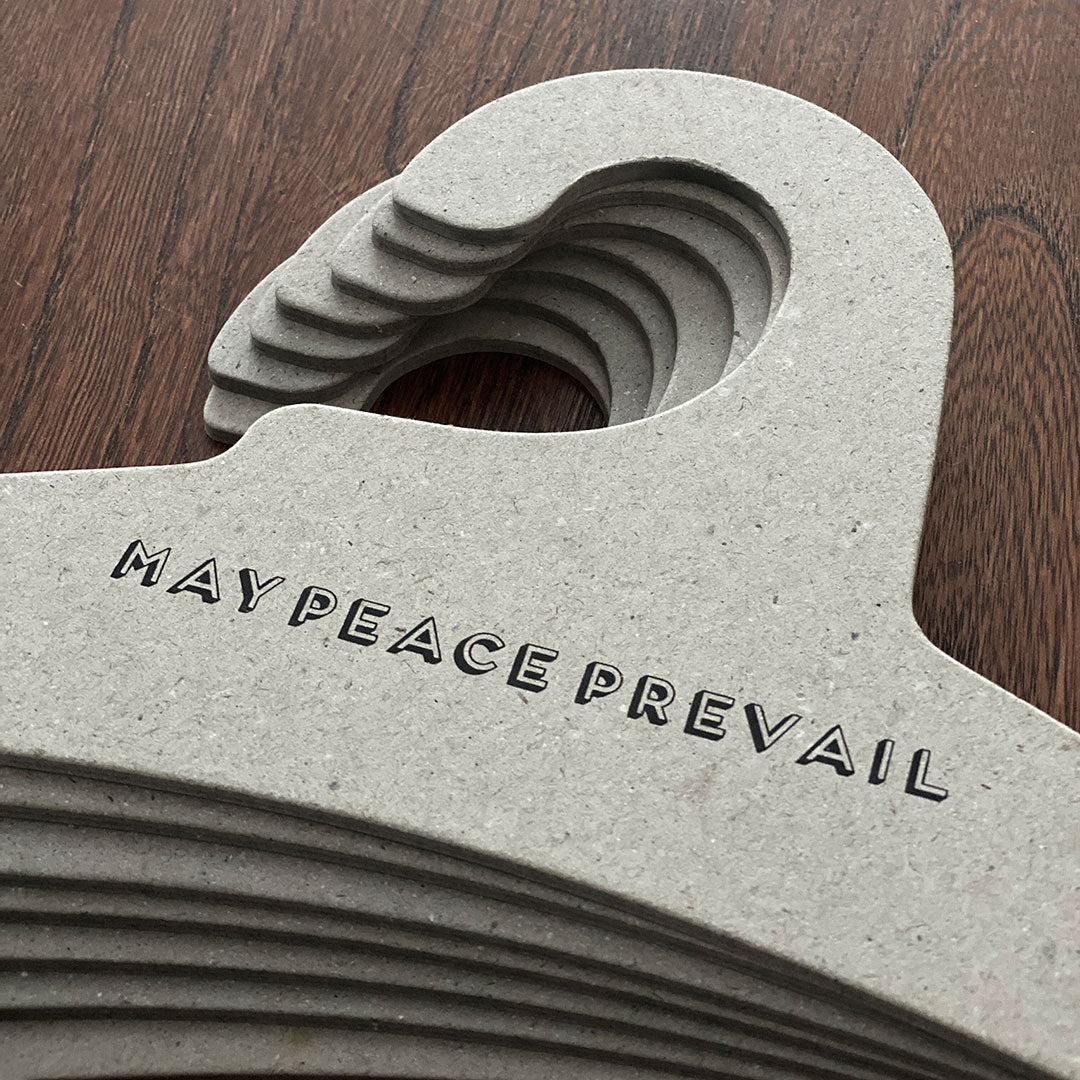 Perchas de cartón reciclado con la palabra paz